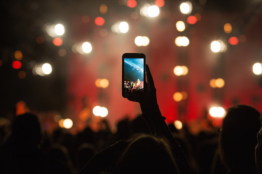fan taking photo with cell phone at a concert