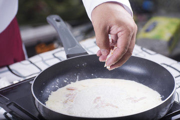 Chef putting bacon to the pan cooking spaghetti carbonara