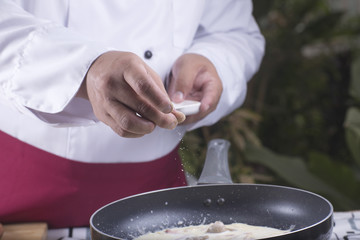 Chef putting pepper to the pan cooking spaghetti carbonara