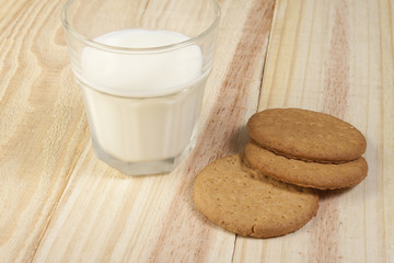 Biscuits and a glass of milk on wooden country table