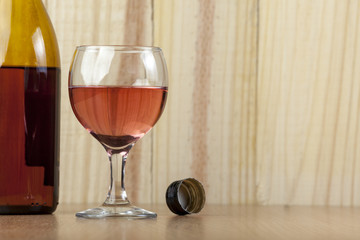 Glass and a bottle of red wine on wooden background