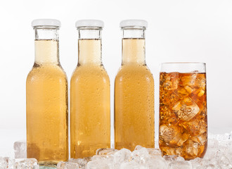 Glass bottles and glass with drink with ice on a neutral background