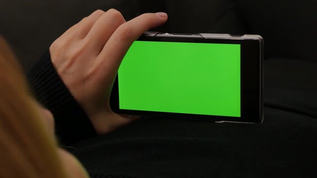 Looking at green screen on smart phone 4K 2160p UHD footage - Chroma greenscreen on mobile phone in blond girl hands 4K 3840X2160 UHD video 