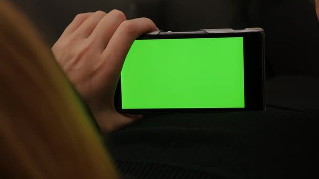 Woman relaxing while looking to green screen on smart phone 4K 2160p UHD footage - Chroma greenscreen on mobile phone in blond girl hands 4K 3840X2160 UHD video 