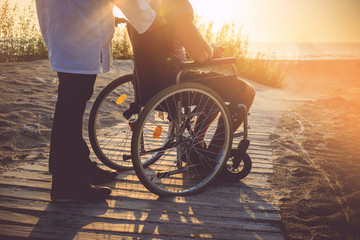 A man on wheelchair and his nurse.