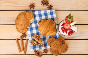 milkshake with strawberries and blueberries, baked croissant on a wooden background