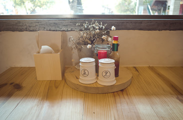 Pepper, salt, spicy sauce and napkin on a wood table