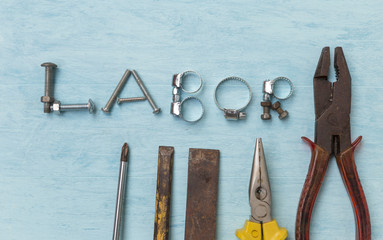 Labor sign concept with tool and spare part on blue wood background