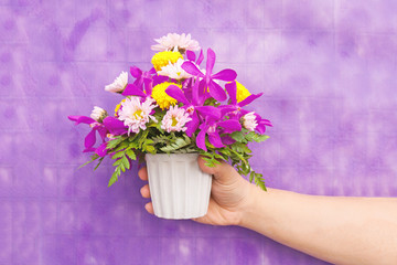 Hand holding bouquet of chrysanthemum and orchid flowers isolate