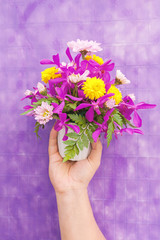 Hand holding bouquet of chrysanthemum and orchid flowers isolate