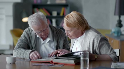 elderly happy couple spend time together and nostalgic. they looking old photo album and smiling