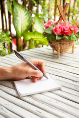Female hand writing in a notebook on wooden table