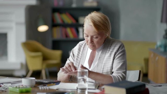 Unhappy troubled elderly woman incredulously looks at a pill. don't want to take medical drugs