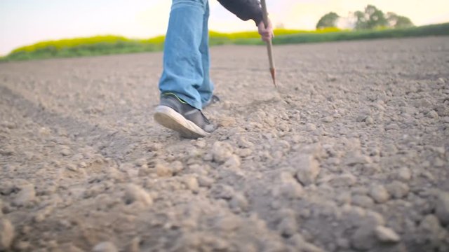 Farmer Using Hoe On Dirt At Farm