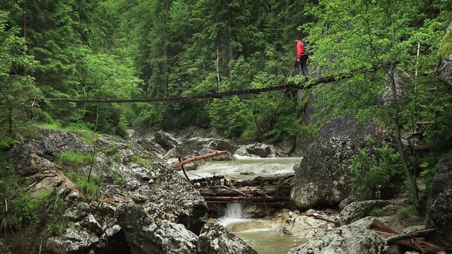 Man hiking on a suspended bridge over a river. Crossing back and forth