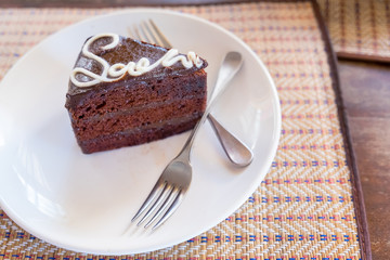 A slice of Dark chocolate cake on a plate and ready to eat,