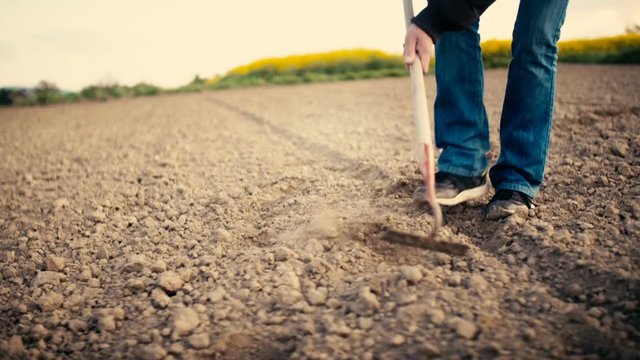 Farmer Using Hoe On Dirt At Farm