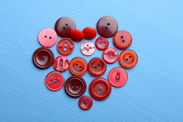 a bunch of buttons red tones are on a blue background in the shape of a heart