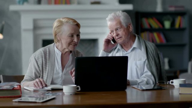 Happy elderly senior couple using laptop computer and smartphone