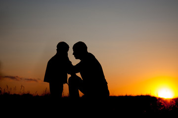 Fototapeta na wymiar Father and little son - silhouettes at sunset