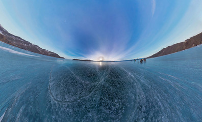 Tourists make the transition ice on Lake Baikal ice at sunset. W
