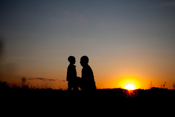 Fototapeta na wymiar Silhouette of a man and his son with sunset background. summertime