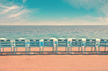 Row of vintage blue chairs on the English Promenade (Promenades des Anglais) with view on the beach...