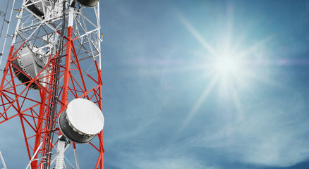 Telecommunications tower and satellite dish telecom network on blue sky with bright sun light