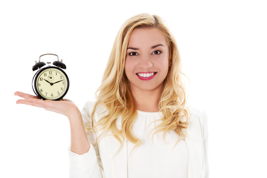 Blond woman showing alarm clock, isolated on white.