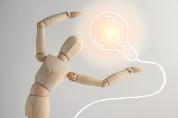 Wooden figure showing up drawing of bulb on white background.jpg
