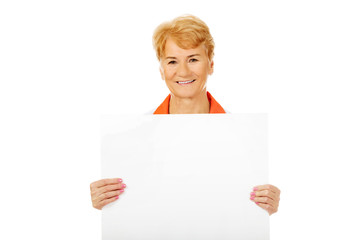 Fototapeta premium Smile elderly female doctor or nurse holding blank banner