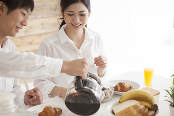 Young couple is eating breakfast with a laugh