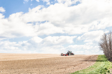Naklejka premium Tractor compresses the soil after planting with rollers.