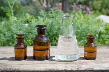 Liquid in chemical ware on a background of plants, fertilizers or pesticides in the garden.