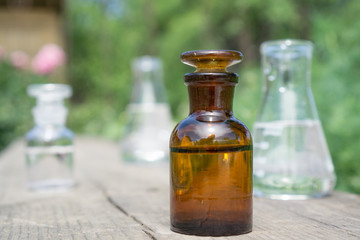Liquid in chemical ware on a background of plants, fertilizers or pesticides in the garden.