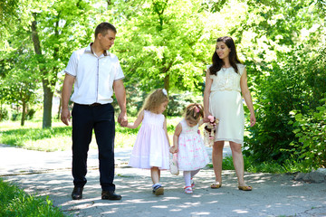 Naklejka premium family with child and pregnant woman walk in summer city park