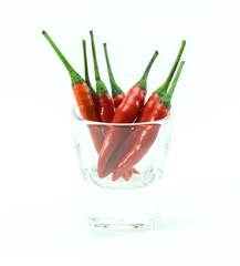 group of chilli peppers in glass cup on white background