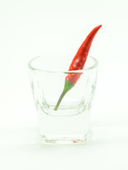 group of chilli peppers in glass cup on white background