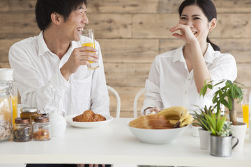 Young couple is eating breakfast with a laugh
