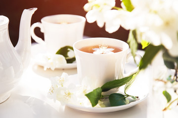 Obraz na płótnie Canvas Close up on jasmine tea with jasmine flower in a glass cup. Tea service in the garden.