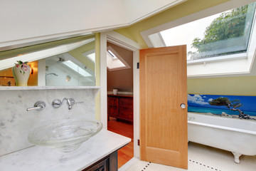 Bright bathroom interior upstairs with bathtub and vaulted ceiling.