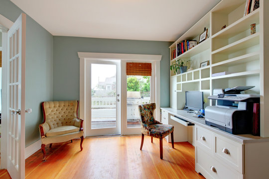 Home office with blue walls and hardwood floor.