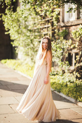 Fototapeta premium Attractive young woman with long dress enjoying her time outside in park sunset background