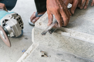 A man in a workshop using an industrial metal grinder to grind down stainless steel
