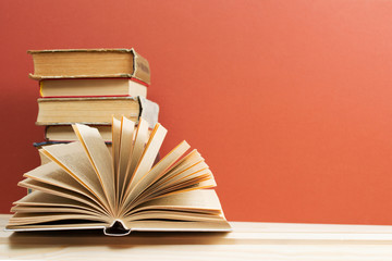 Open book, stack of hardback books on wooden table. Back to school. Copy space