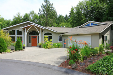 Beautiful beige house with white trim and driveway to garage.