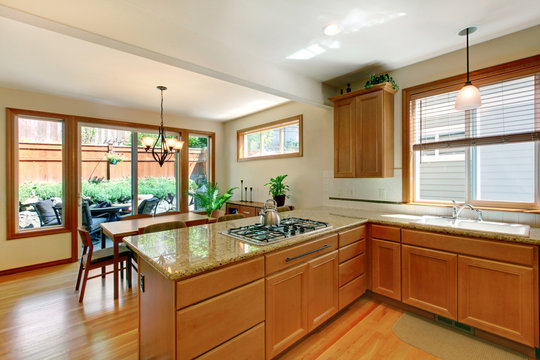 Brown and white kitchen room with hardwood floor, cabinets and eating area.