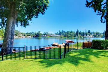 Backyard area with well kept lawn and metal fence. Beautiful water view