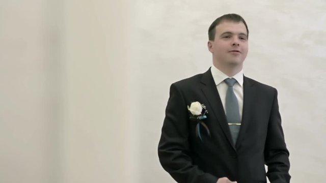 The groom adjusts his tie clip in the mirror