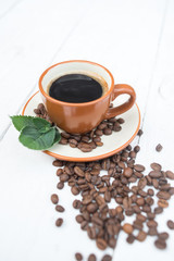 Coffee cup, beans and mint on a white wood background.